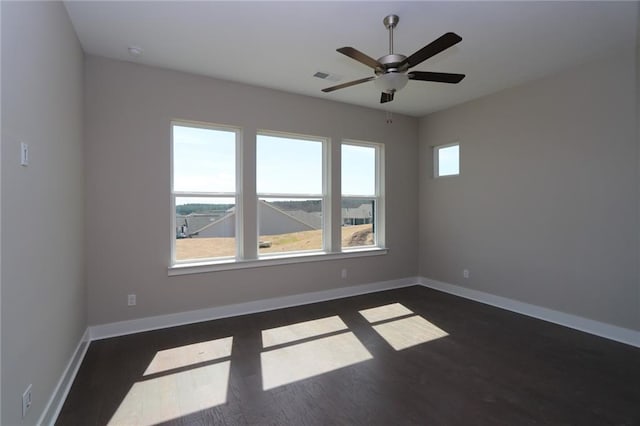 spare room with a ceiling fan, dark wood-type flooring, baseboards, and visible vents