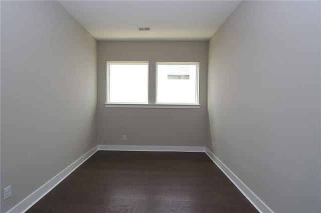 empty room with visible vents, baseboards, and dark wood-type flooring