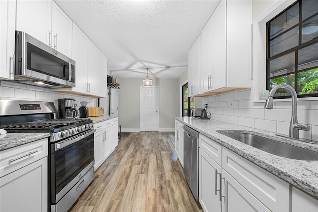 kitchen with baseboards, a sink, white cabinets, and stainless steel appliances