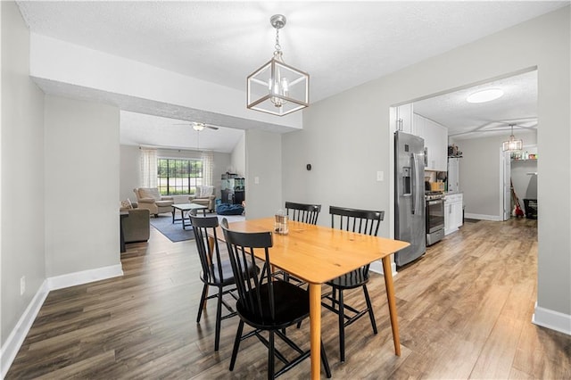 dining room with baseboards, light wood finished floors, and a textured ceiling