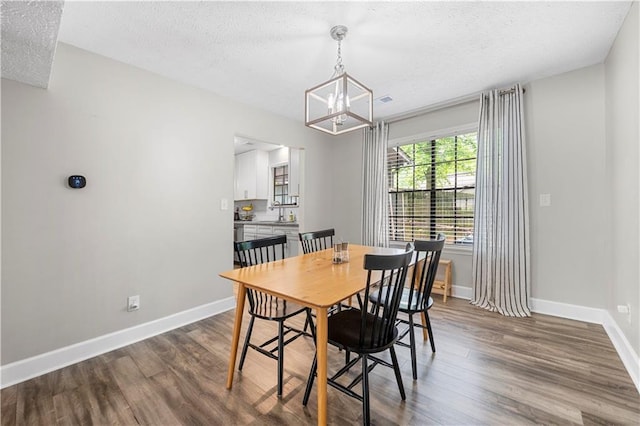 dining space featuring an inviting chandelier, a textured ceiling, and wood finished floors