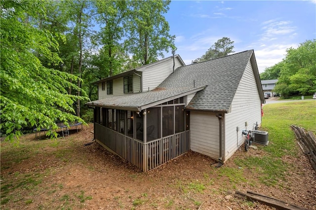 back of property featuring a shingled roof, central AC unit, a sunroom, and a trampoline