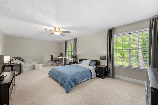 bedroom with a ceiling fan, baseboards, light carpet, and a textured ceiling