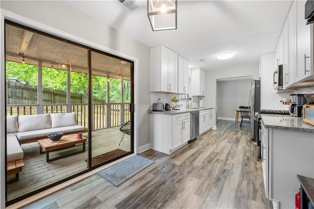 kitchen with a sink, light wood-style floors, stainless steel appliances, white cabinetry, and visible vents