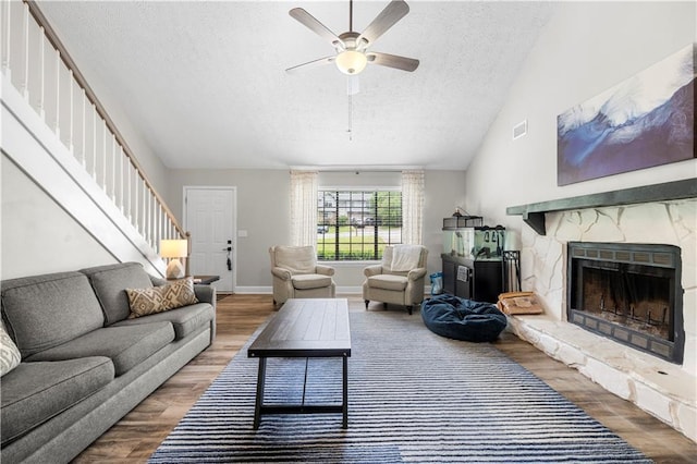 living room with a fireplace, stairs, a textured ceiling, and wood finished floors