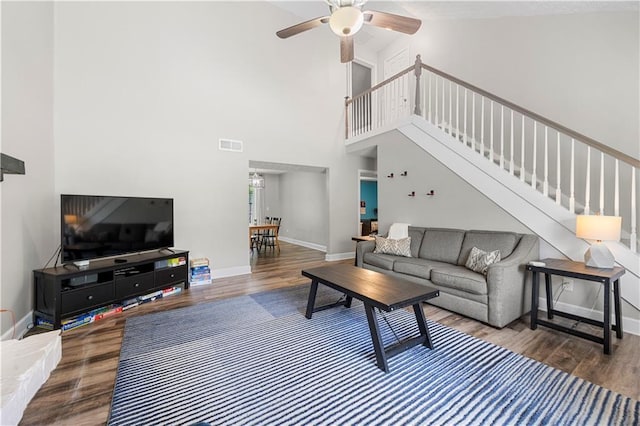 living area featuring stairs, a ceiling fan, visible vents, and wood finished floors