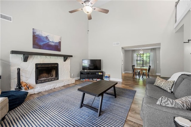 living room featuring visible vents, wood finished floors, baseboards, a high ceiling, and a ceiling fan
