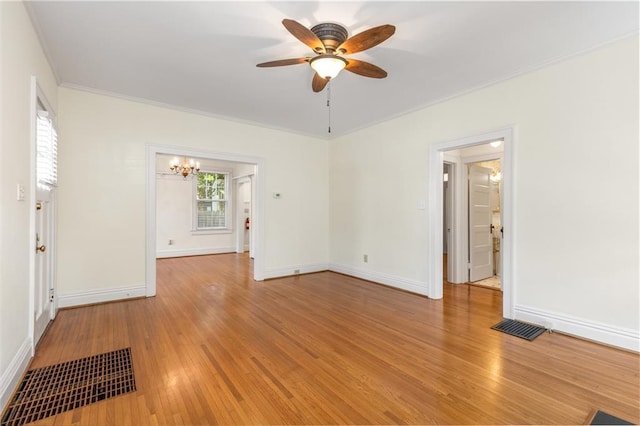 empty room with a chandelier, ceiling fan, light wood-type flooring, baseboards, and ornamental molding
