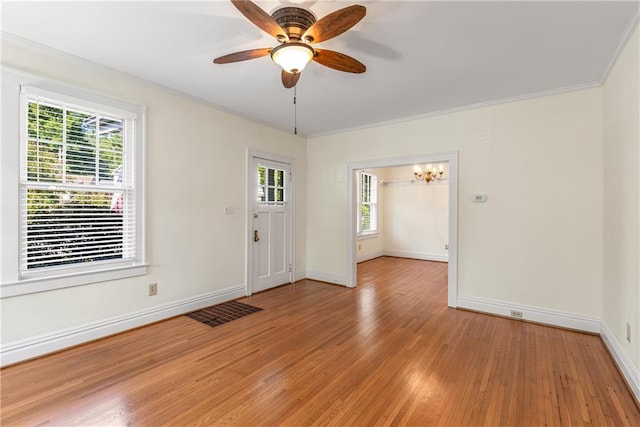 unfurnished room with healthy amount of natural light, baseboards, light wood-type flooring, and crown molding