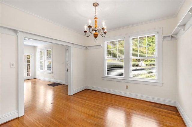 unfurnished dining area featuring a chandelier, light wood-type flooring, plenty of natural light, baseboards, and crown molding