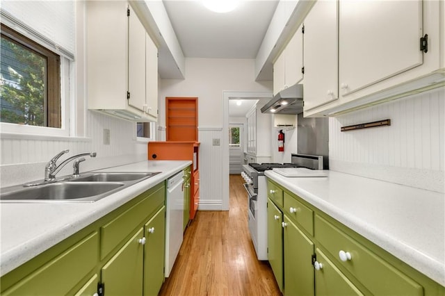 kitchen featuring a sink, stainless steel stove, under cabinet range hood, light countertops, and light wood finished floors