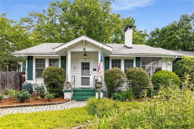 view of front of house with a chimney, fence, and a shingled roof