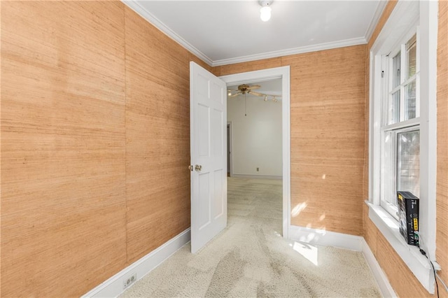 empty room with crown molding, baseboards, carpet flooring, and a ceiling fan