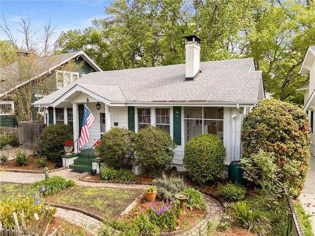 view of front of property featuring a chimney, a shingled roof, and fence