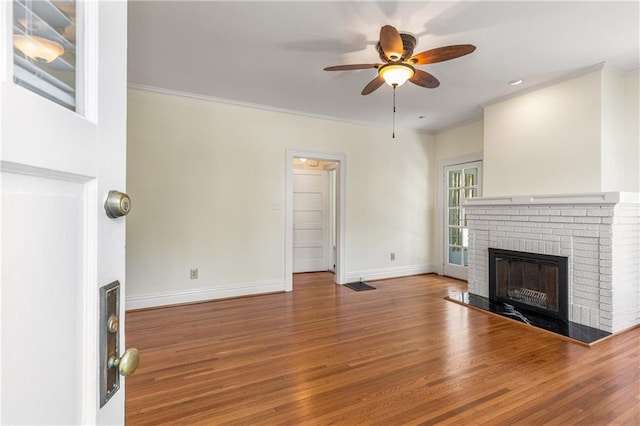 unfurnished living room with a fireplace, ceiling fan, baseboards, wood finished floors, and crown molding