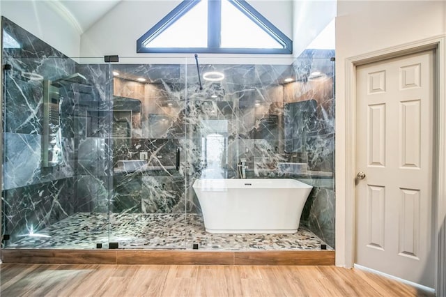 bathroom featuring lofted ceiling, wood finished floors, a freestanding bath, and a shower stall