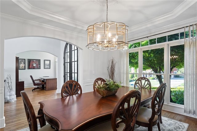 dining room with arched walkways, a chandelier, wood finished floors, ornamental molding, and a tray ceiling