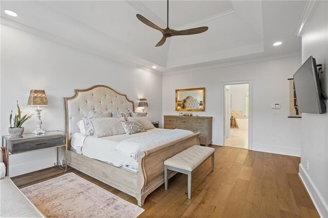 bedroom featuring recessed lighting, wood finished floors, ornamental molding, a tray ceiling, and baseboards