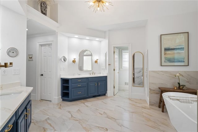 bathroom with two vanities, a freestanding bath, marble finish flooring, and a chandelier