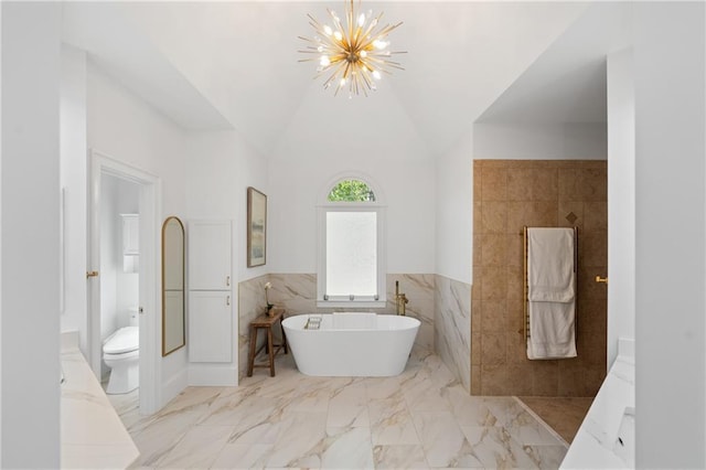 full bathroom with a chandelier, tile walls, a freestanding bath, toilet, and marble tiled flooring