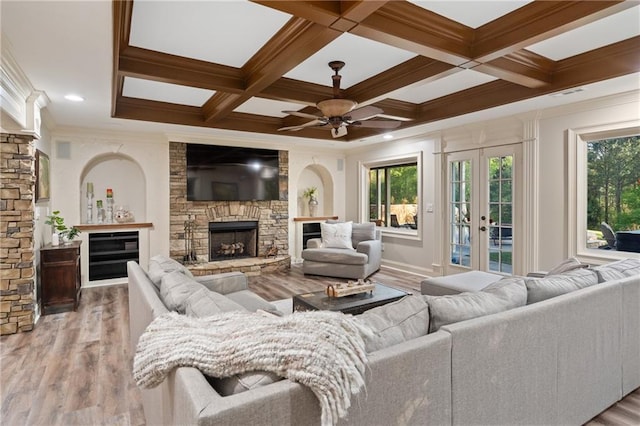 living area featuring a fireplace, wood finished floors, a ceiling fan, crown molding, and beam ceiling