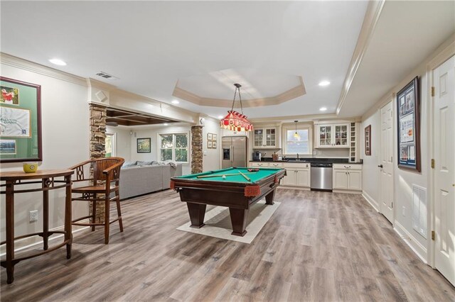 playroom featuring a raised ceiling, crown molding, light wood-style flooring, a sink, and healthy amount of natural light