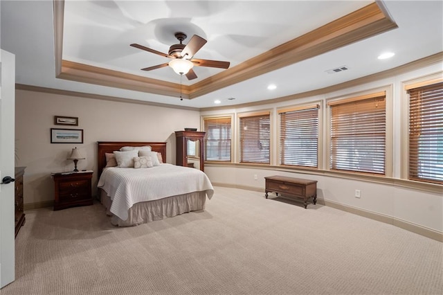 carpeted bedroom featuring a tray ceiling, crown molding, baseboards, recessed lighting, and ceiling fan