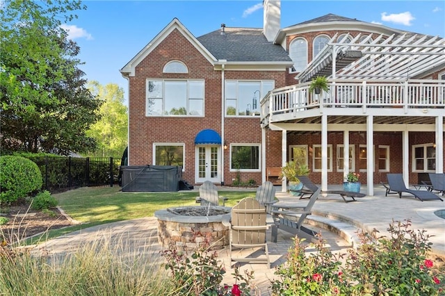 rear view of house featuring brick siding, a hot tub, an outdoor fire pit, a deck, and a patio area