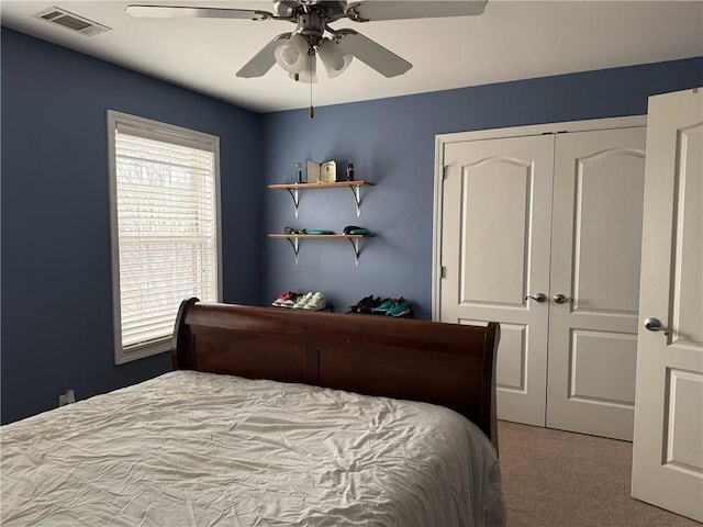 bedroom with light colored carpet, ceiling fan, and a closet