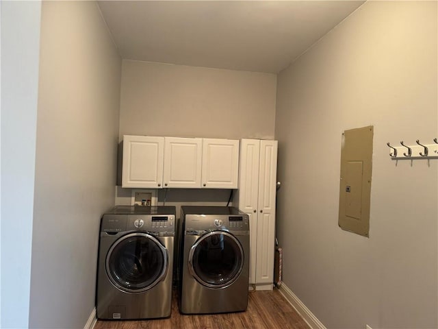 clothes washing area featuring cabinets, washing machine and clothes dryer, electric panel, and dark hardwood / wood-style flooring