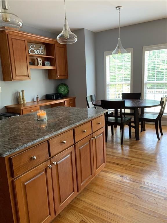 kitchen featuring hanging light fixtures, light wood-type flooring, and dark stone counters