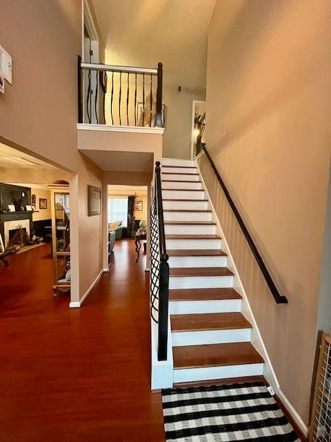 stairs with wood-type flooring and a high ceiling