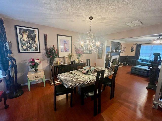 dining space featuring hardwood / wood-style floors, a notable chandelier, and a textured ceiling