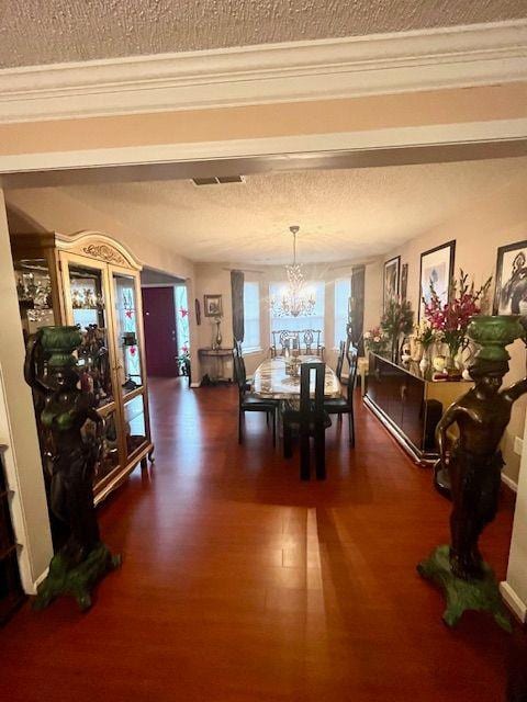 dining room featuring ornamental molding, dark hardwood / wood-style floors, a textured ceiling, and an inviting chandelier