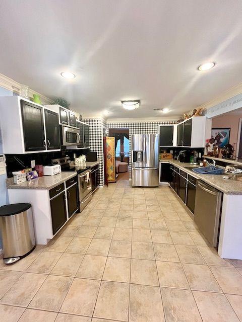 kitchen featuring light stone countertops, backsplash, stainless steel appliances, and sink