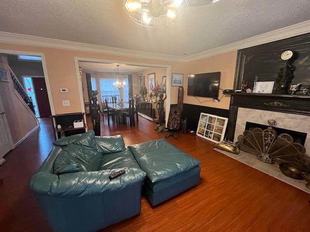 living room with wood-type flooring, a textured ceiling, and ornamental molding