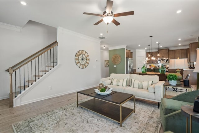 living area with baseboards, visible vents, light wood finished floors, stairs, and crown molding