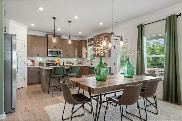 dining space featuring recessed lighting, light wood-type flooring, and ornamental molding