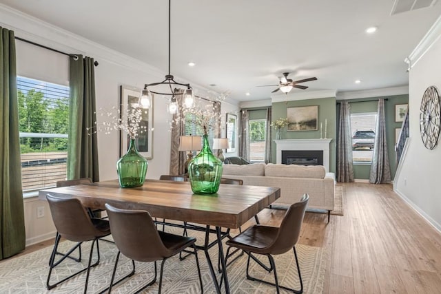 dining space with visible vents, recessed lighting, a glass covered fireplace, crown molding, and light wood-type flooring