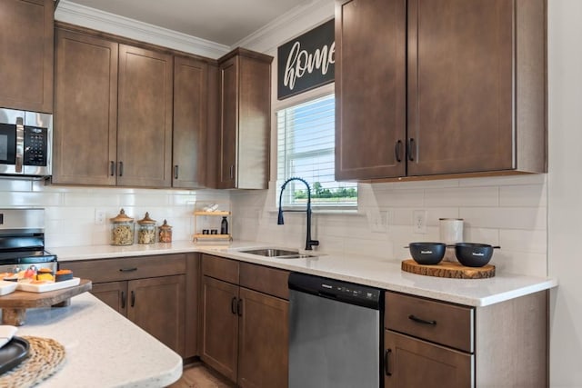 kitchen with a sink, stainless steel appliances, tasteful backsplash, and ornamental molding