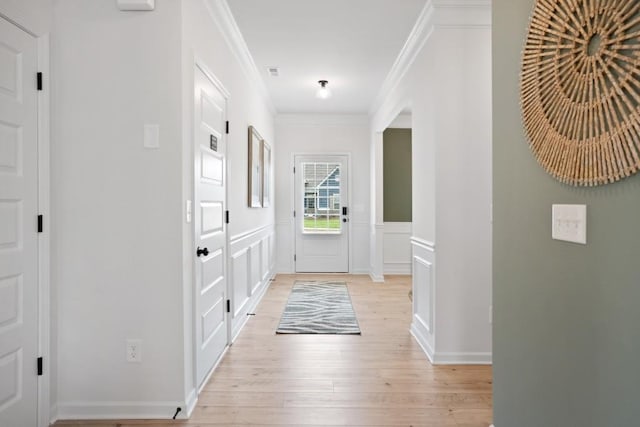 foyer entrance with a decorative wall, a wainscoted wall, light wood-style floors, and ornamental molding