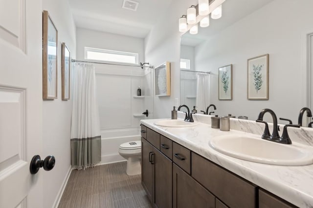 full bath featuring a sink, visible vents, toilet, and shower / tub combo