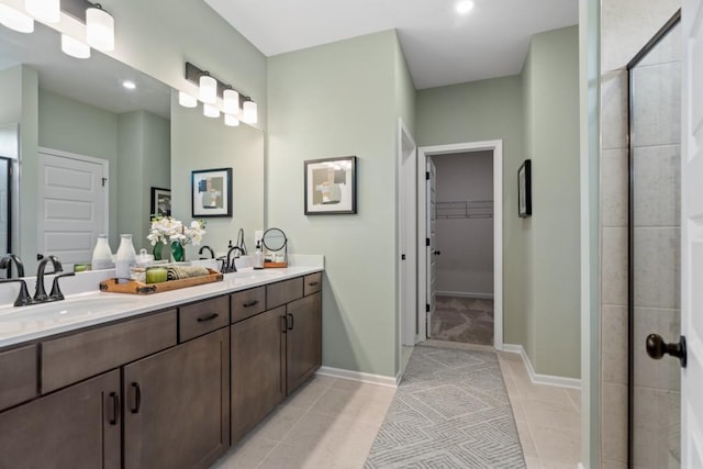 full bathroom with a shower stall, a spacious closet, tile patterned floors, and a sink