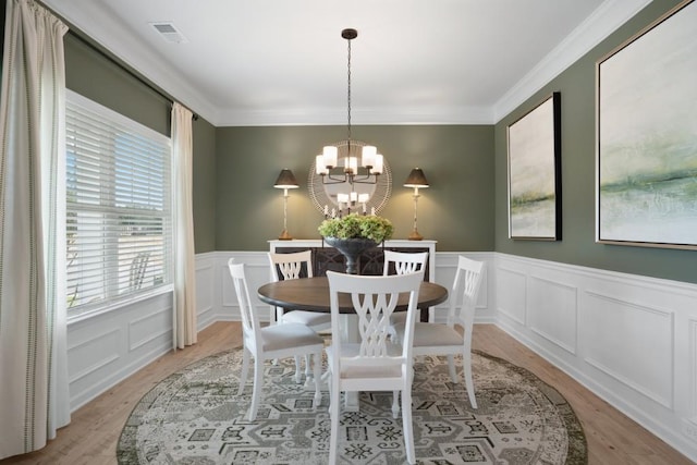 dining room with a chandelier, visible vents, light wood finished floors, and crown molding