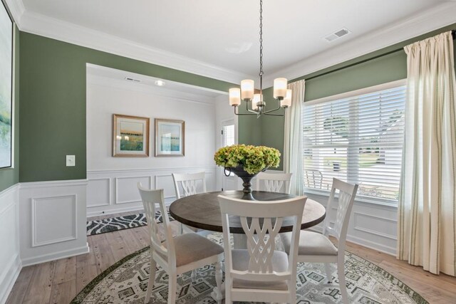 dining space featuring crown molding, light wood finished floors, visible vents, and a wealth of natural light