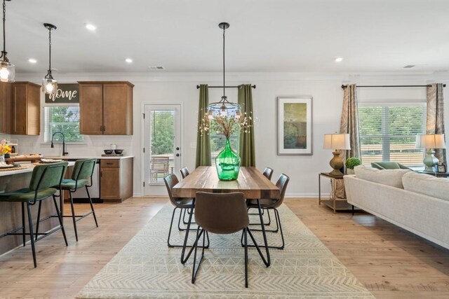 dining area with visible vents, light wood-style flooring, and ornamental molding