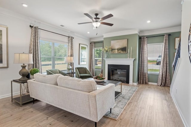 living room with a glass covered fireplace, ornamental molding, baseboards, and wood finished floors