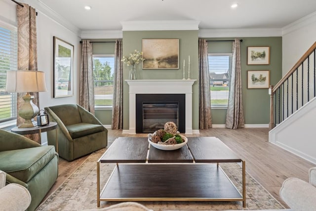 living room featuring a fireplace with flush hearth, ornamental molding, wood finished floors, baseboards, and stairs