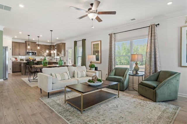 living area featuring visible vents, a healthy amount of sunlight, and ornamental molding