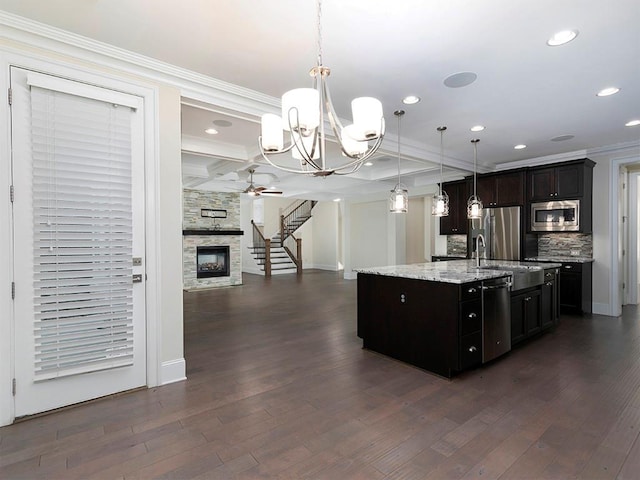 kitchen featuring appliances with stainless steel finishes, decorative light fixtures, dark hardwood / wood-style floors, and a center island with sink